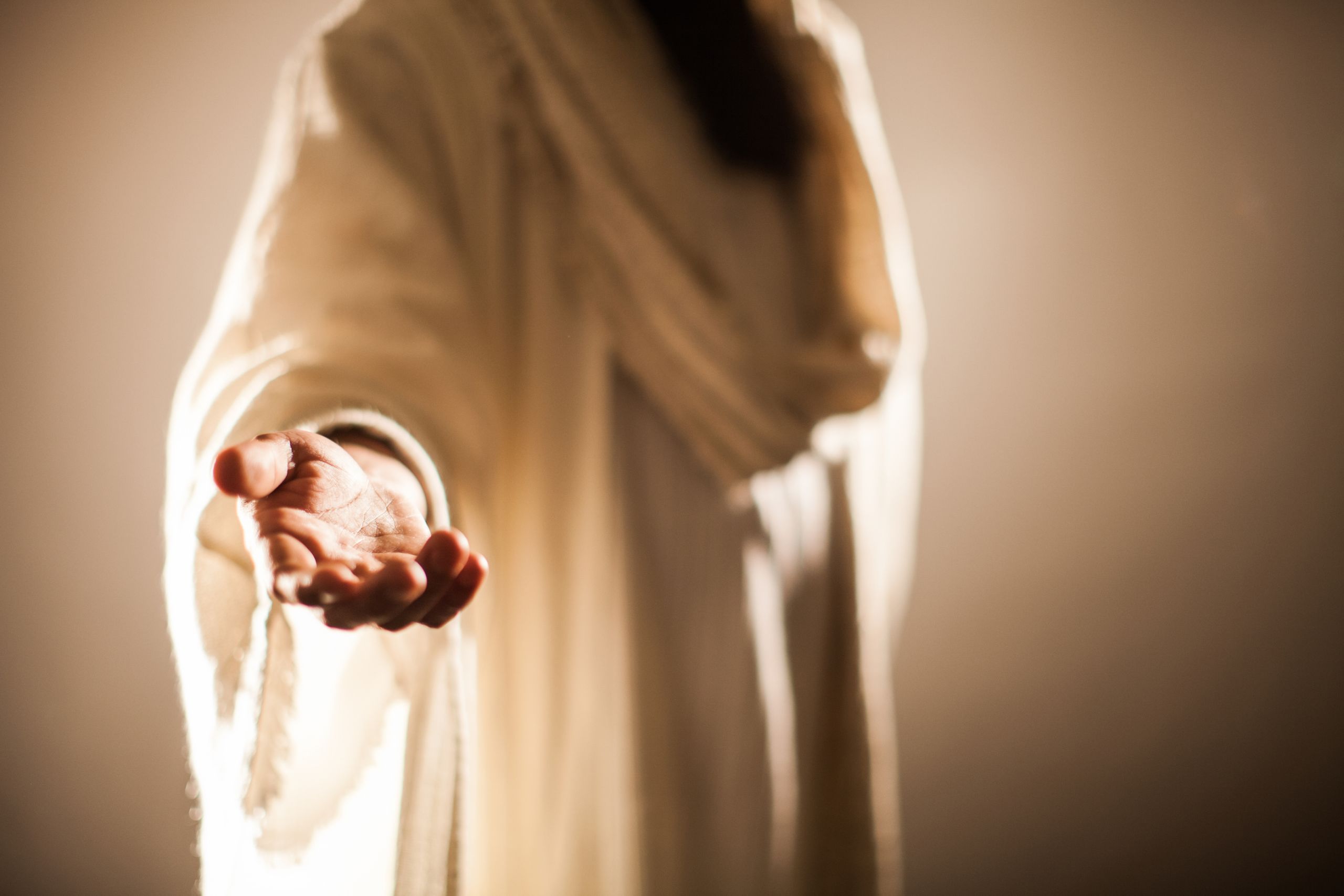 Jesus is dressed in a white robe extending His hand out to you.